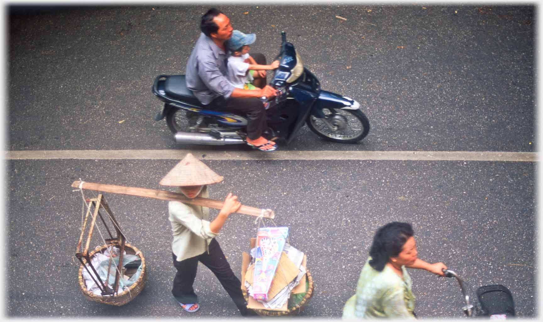 Woman walking along road with card/paper in one pannier.