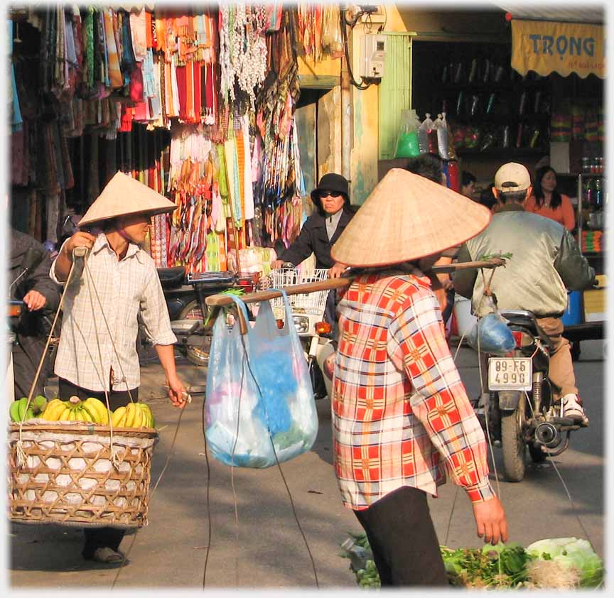 Two hawkers in conical hats with panniers.