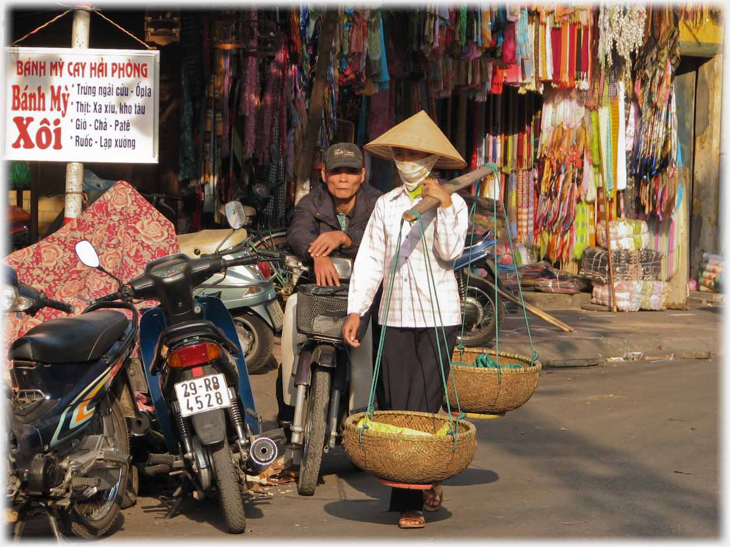 Woman with empty pannier, conical hat ahd face mask.