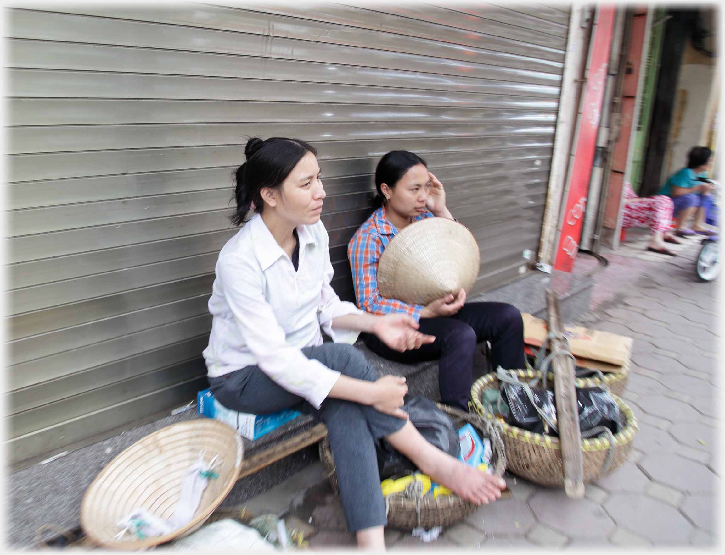 Two women resting on a door step with their panniers.