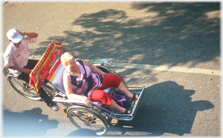 Large woman occupying the whole of a rickshaw herself.