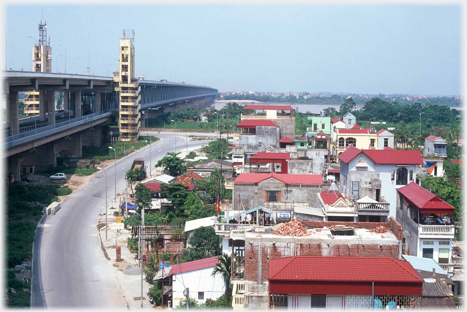 Road and housing with large bridge to left.