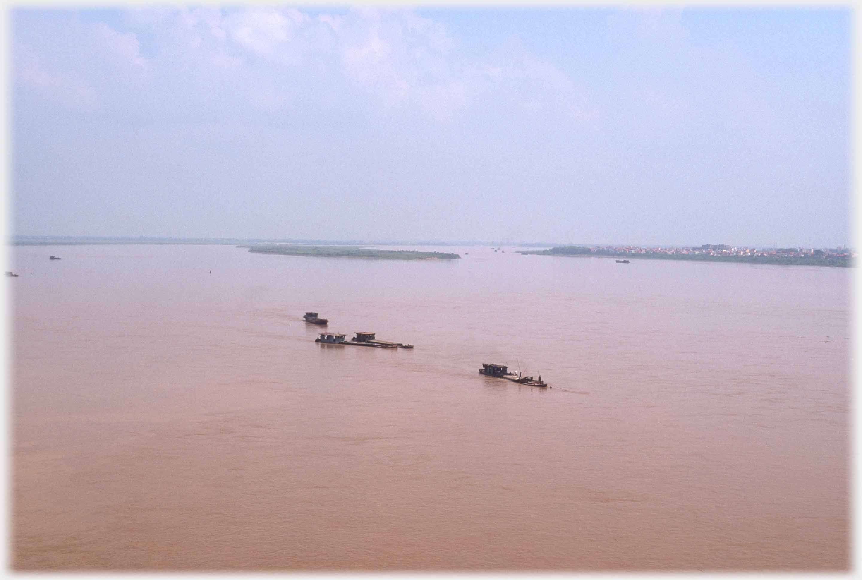 Wide view of the river with four barges in centre of picture.