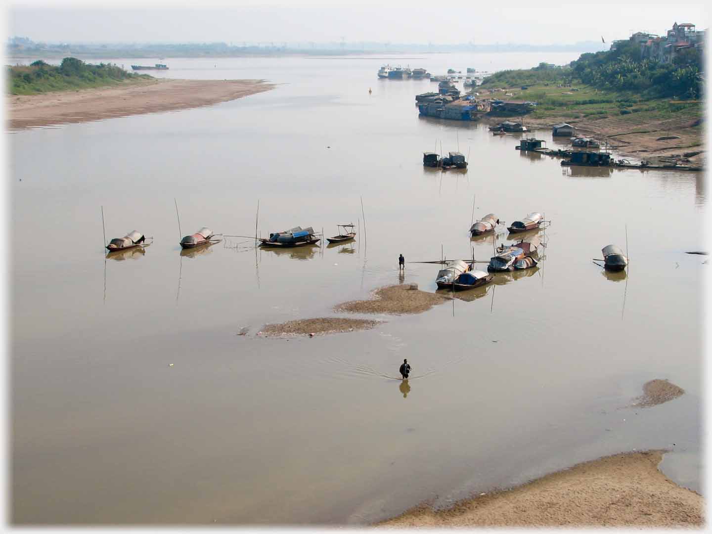 Man walking from houseboats in river towards bank.