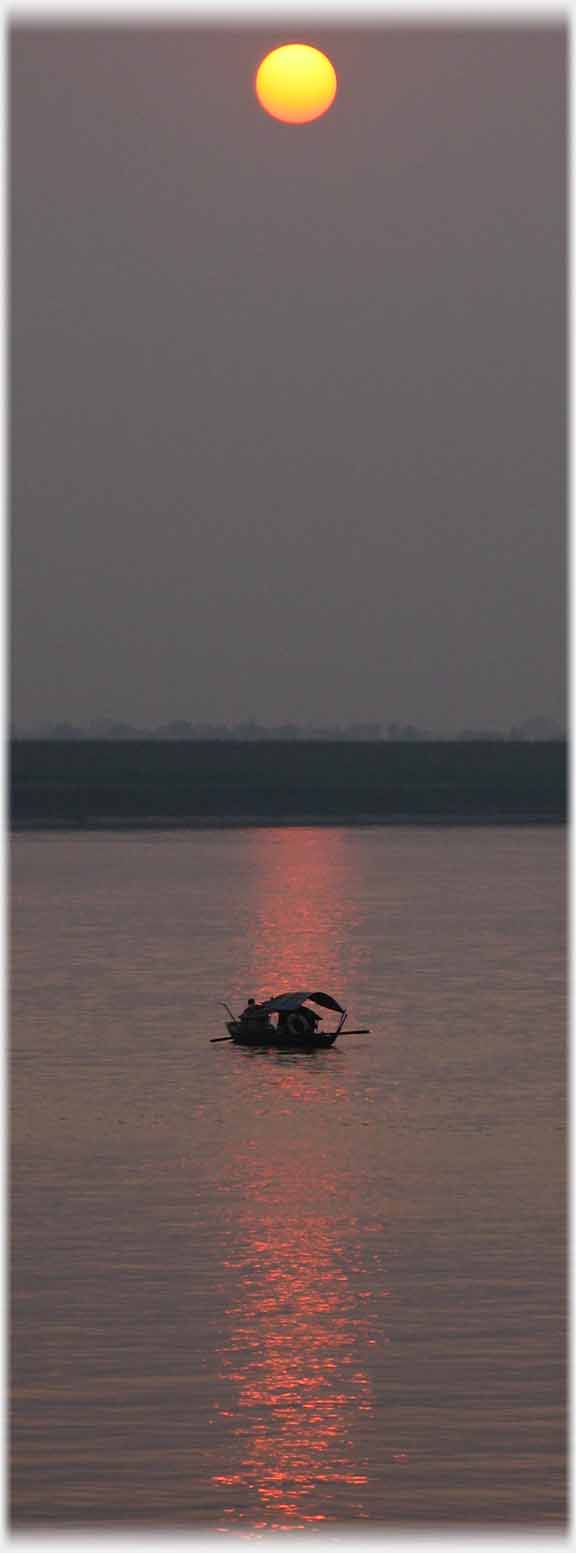 Small boat on column of reflected sun.