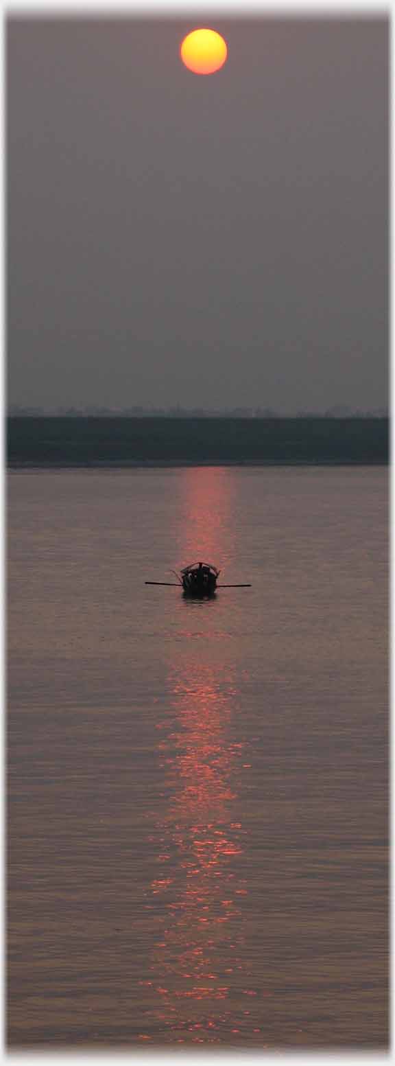Small boat with oars on column of reflected sun.