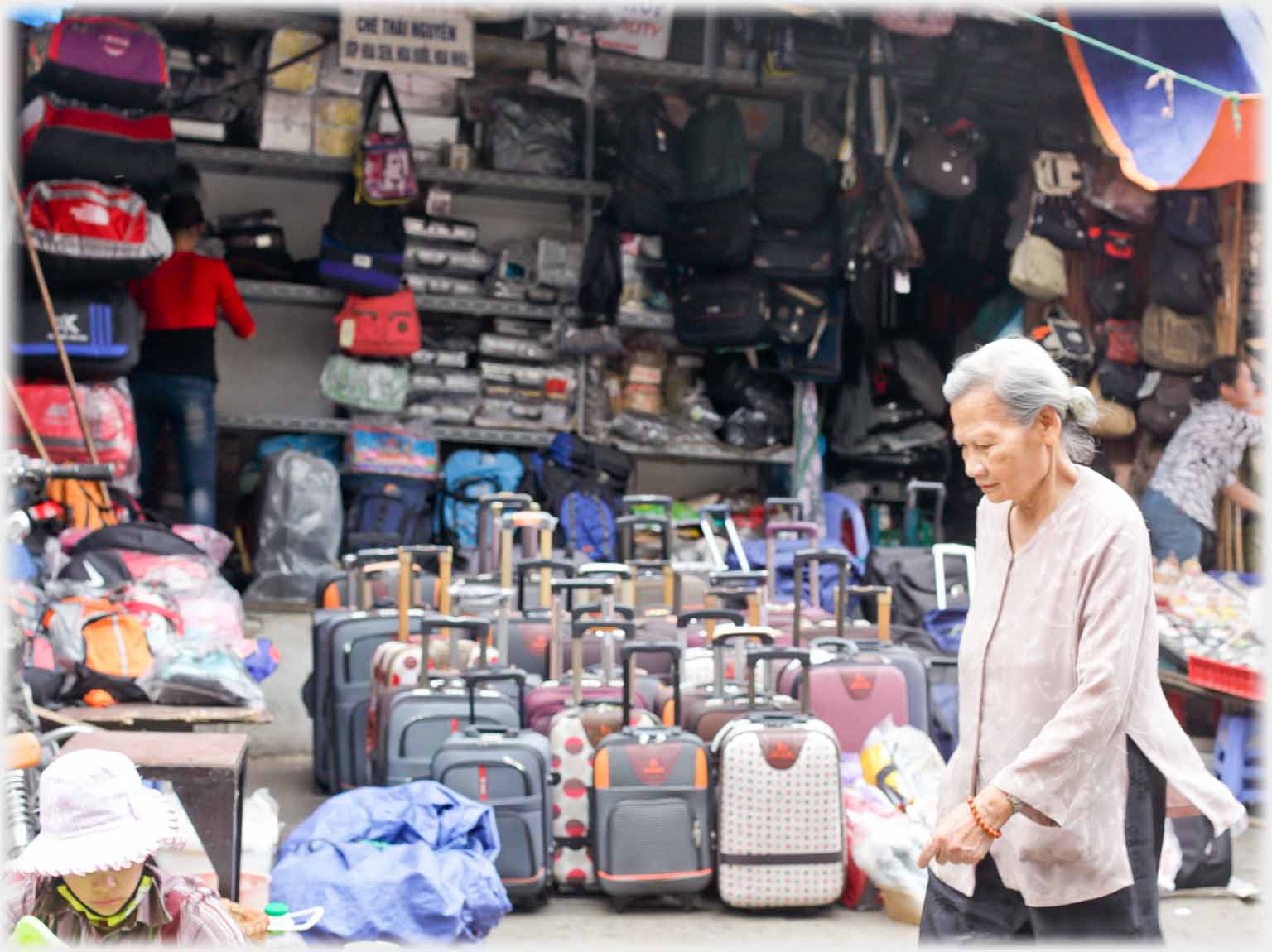 Shop stacked with luggage, woman walking past.