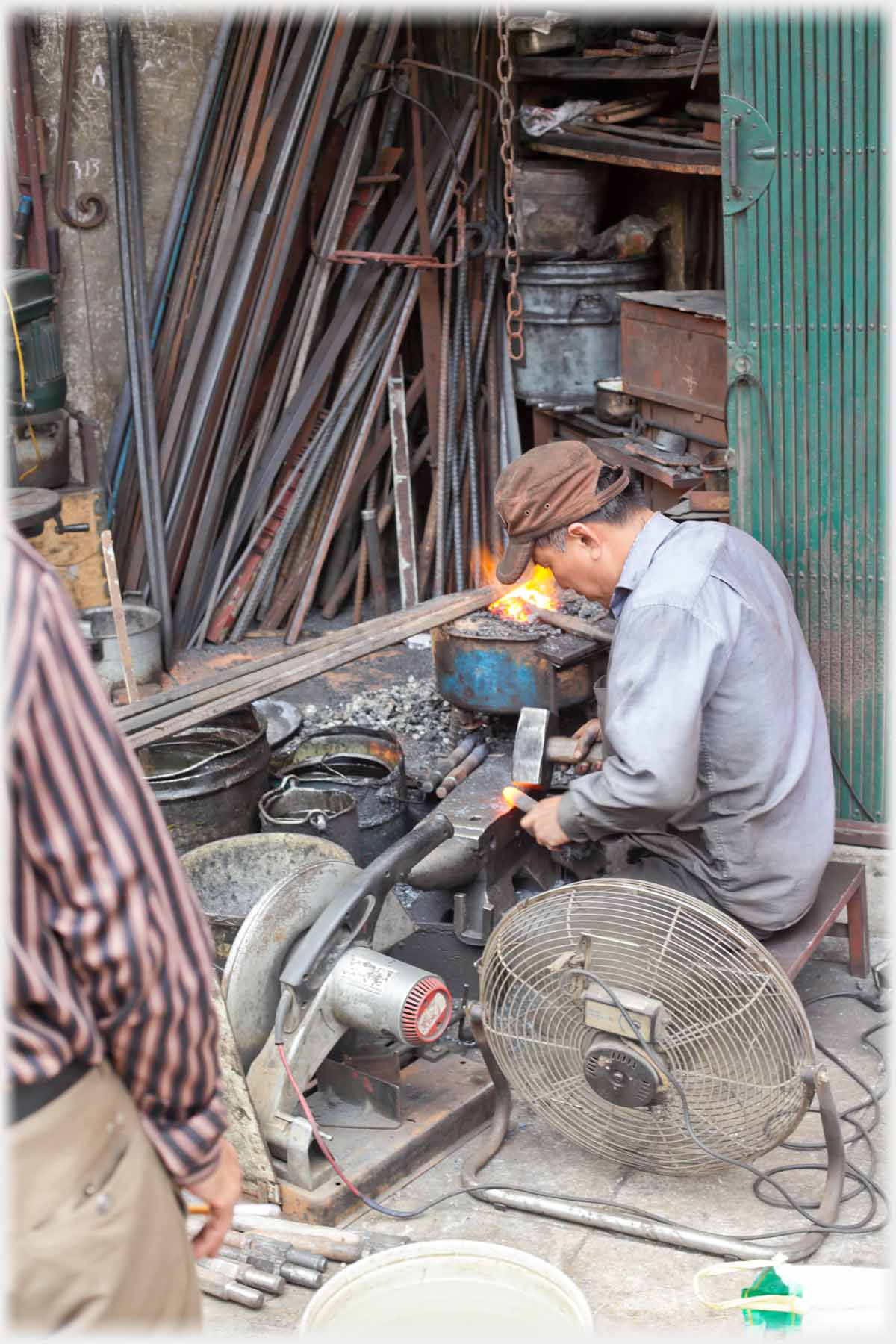 Man hammering red-hot iron on anvil.