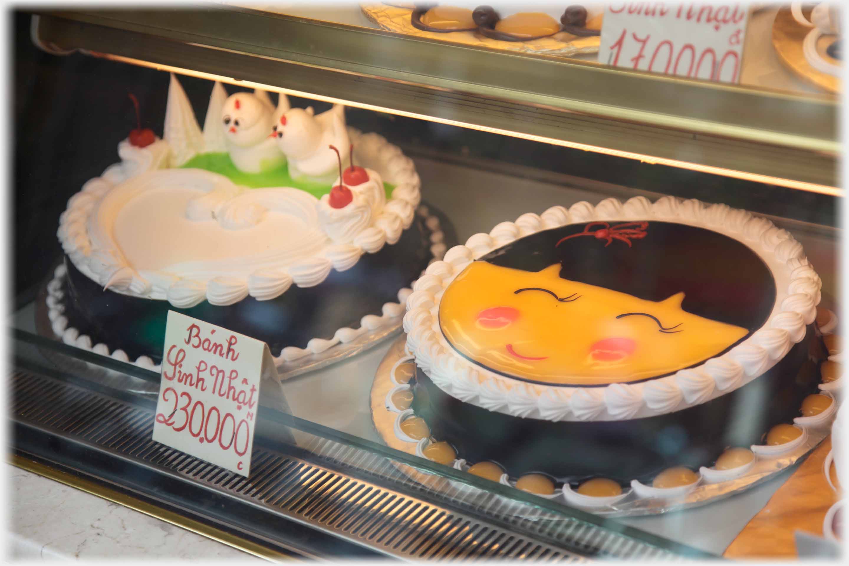 Two decorated cakes one as a face, the other with two birds.