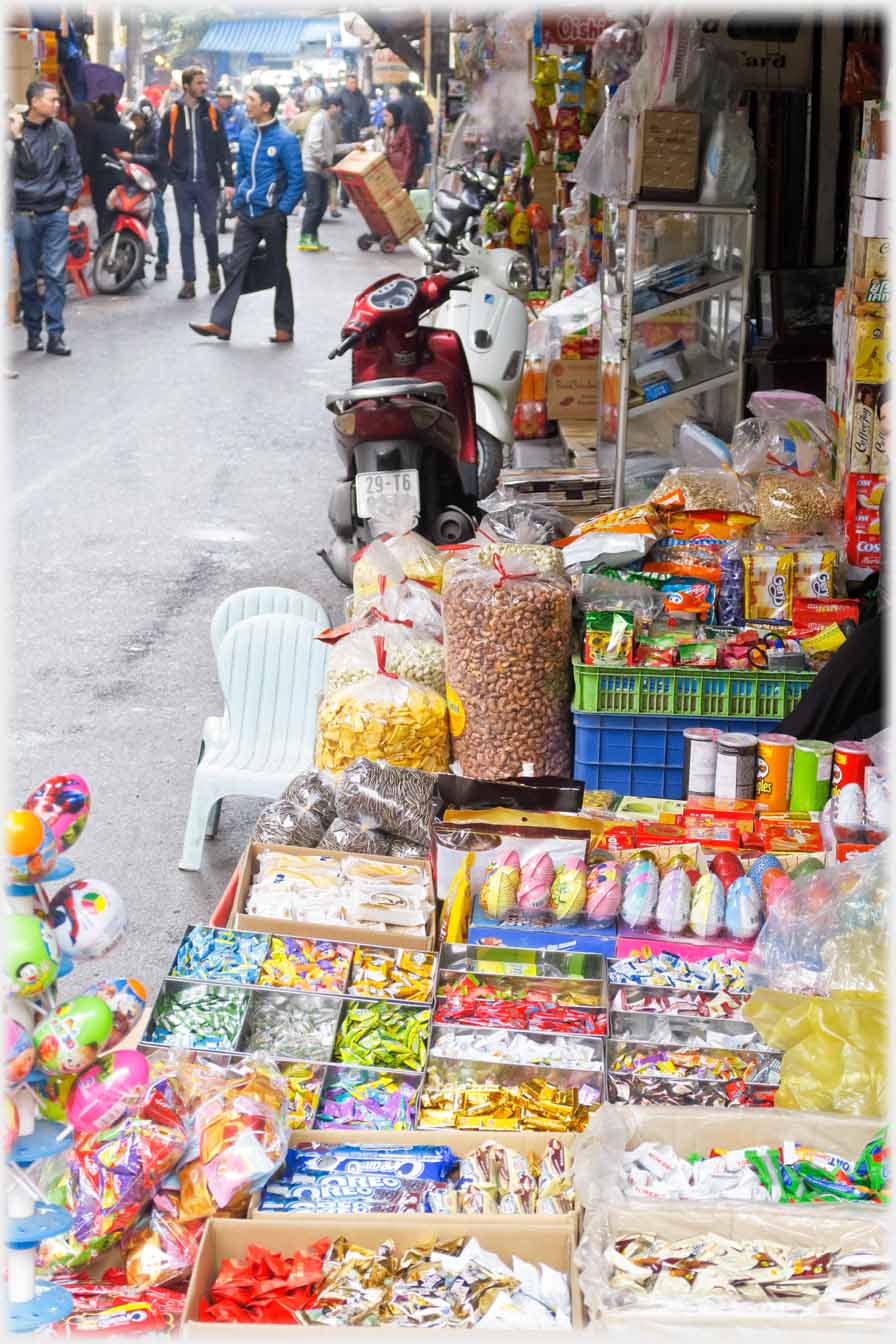 The containers of sweets from a shop flooding out onto the pavement with street beyond.