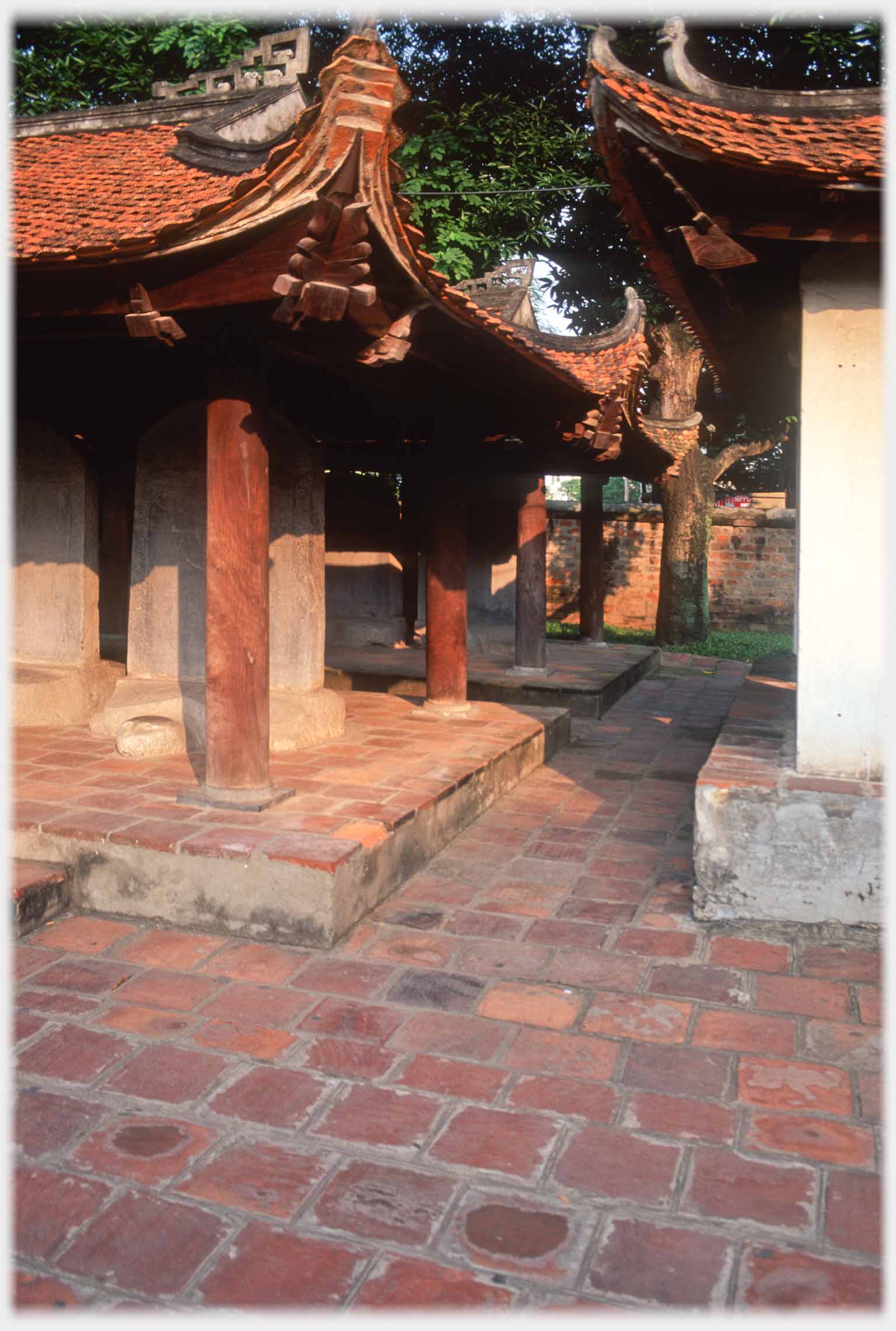 Corner of two buildings with passage between, upturned eaves conspicuous.