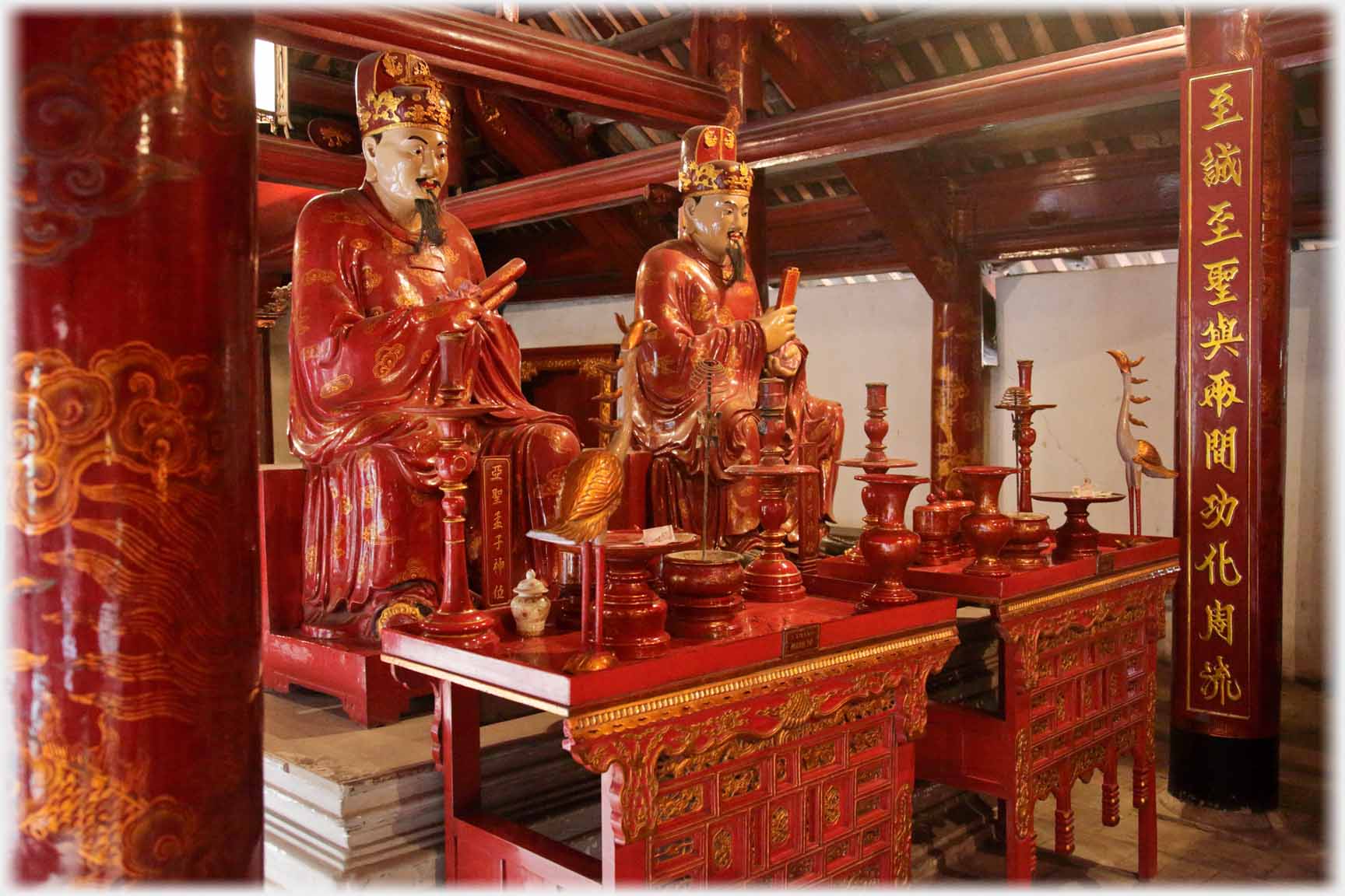 Two red and gold seated figures looking to the right.