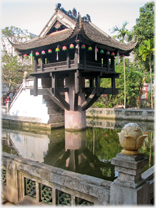 Pagoda on single pillar in pool.