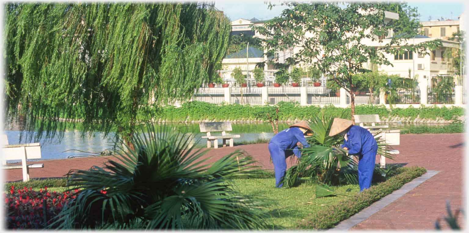 Two women tending plant in blue suits and hats.