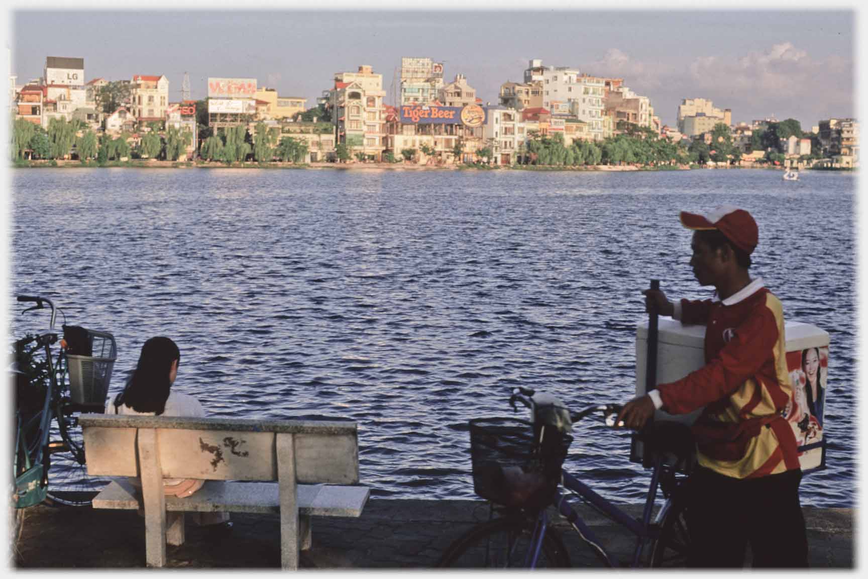 Man with converted cycles, girl on seat by lake.