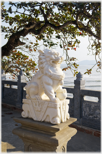 One of pair of lions with sea beyond.