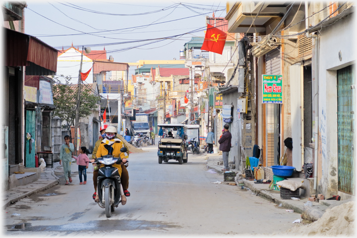 Main street motorcyclist and electric taxi.