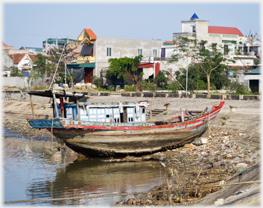 Battered older boat on shore.