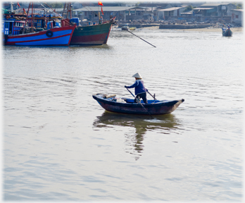 Woman standing rowing her boat.