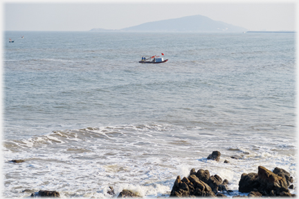 Small boat at sea with island in background.