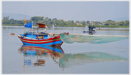 Fishing boat with net draped over long pole to the front.