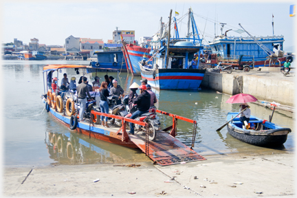 Ferry full and rowing boat returns to position on the ramp - umbrella up.