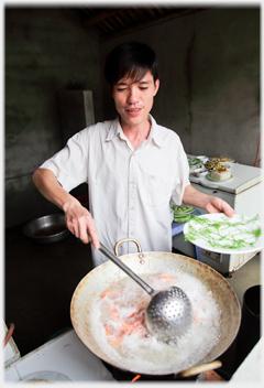 Loi cooking with a large wok.