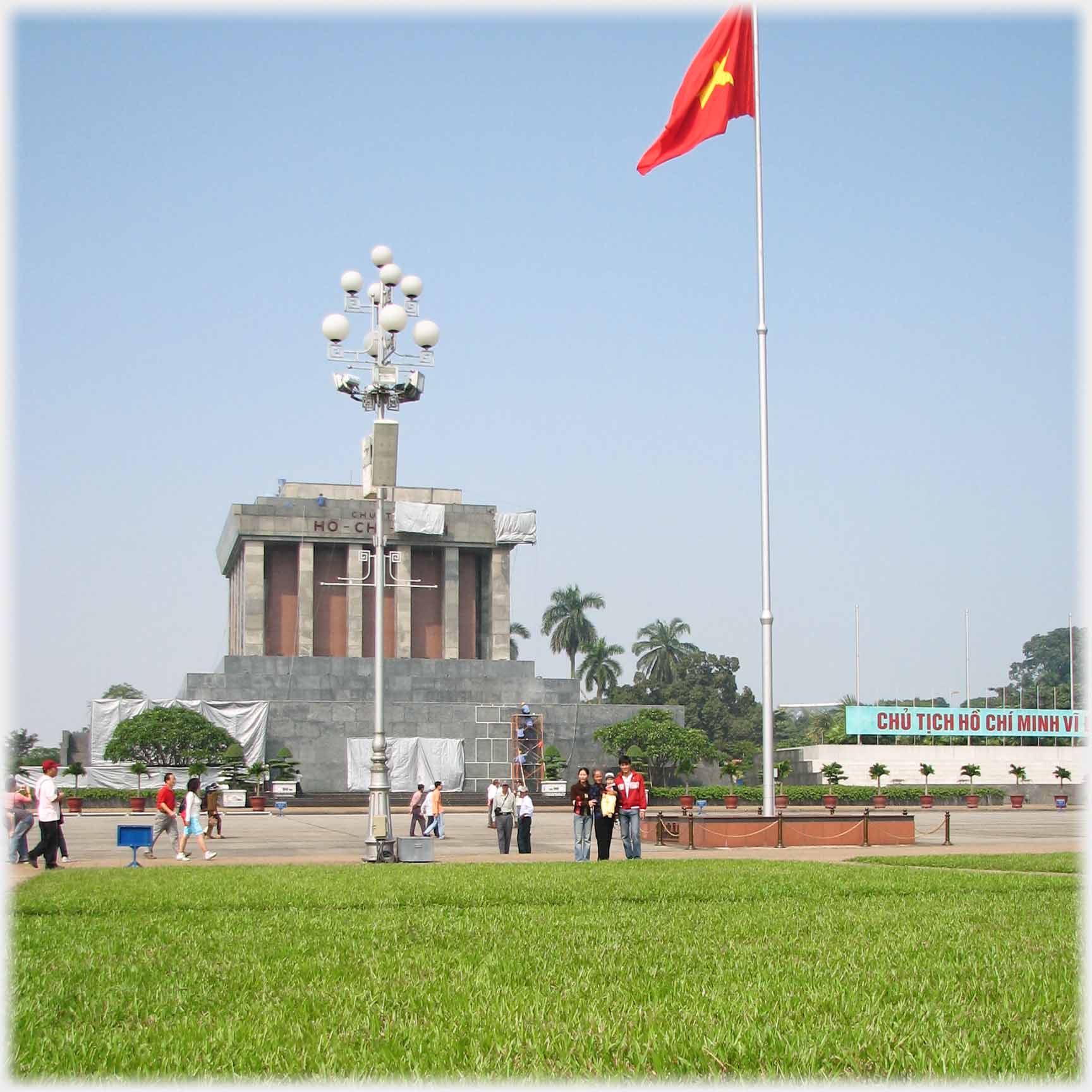 Front of mausoleum, family at edge of grass, flagpole.