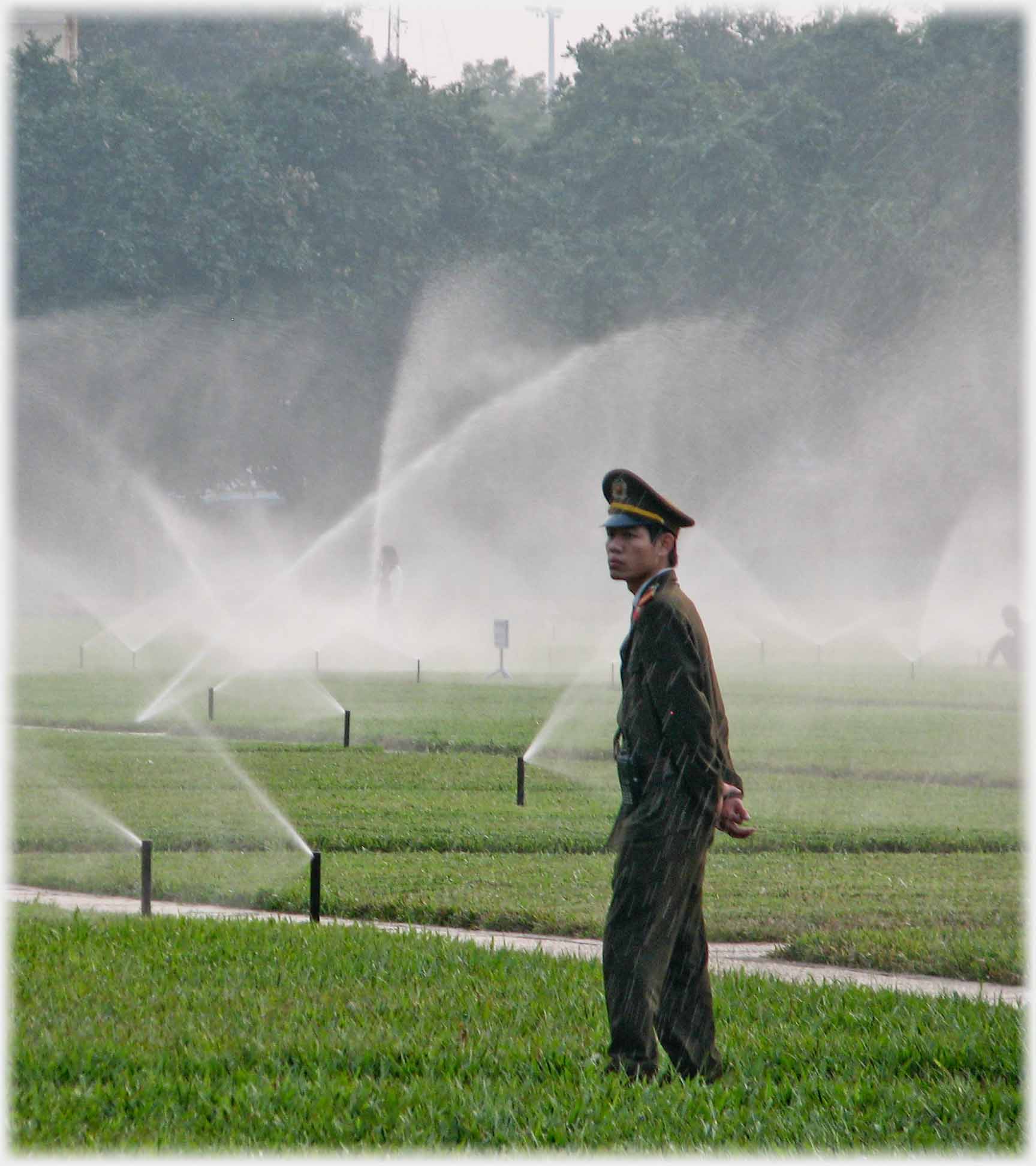 Soldier against background of sprinklers, spay over him.