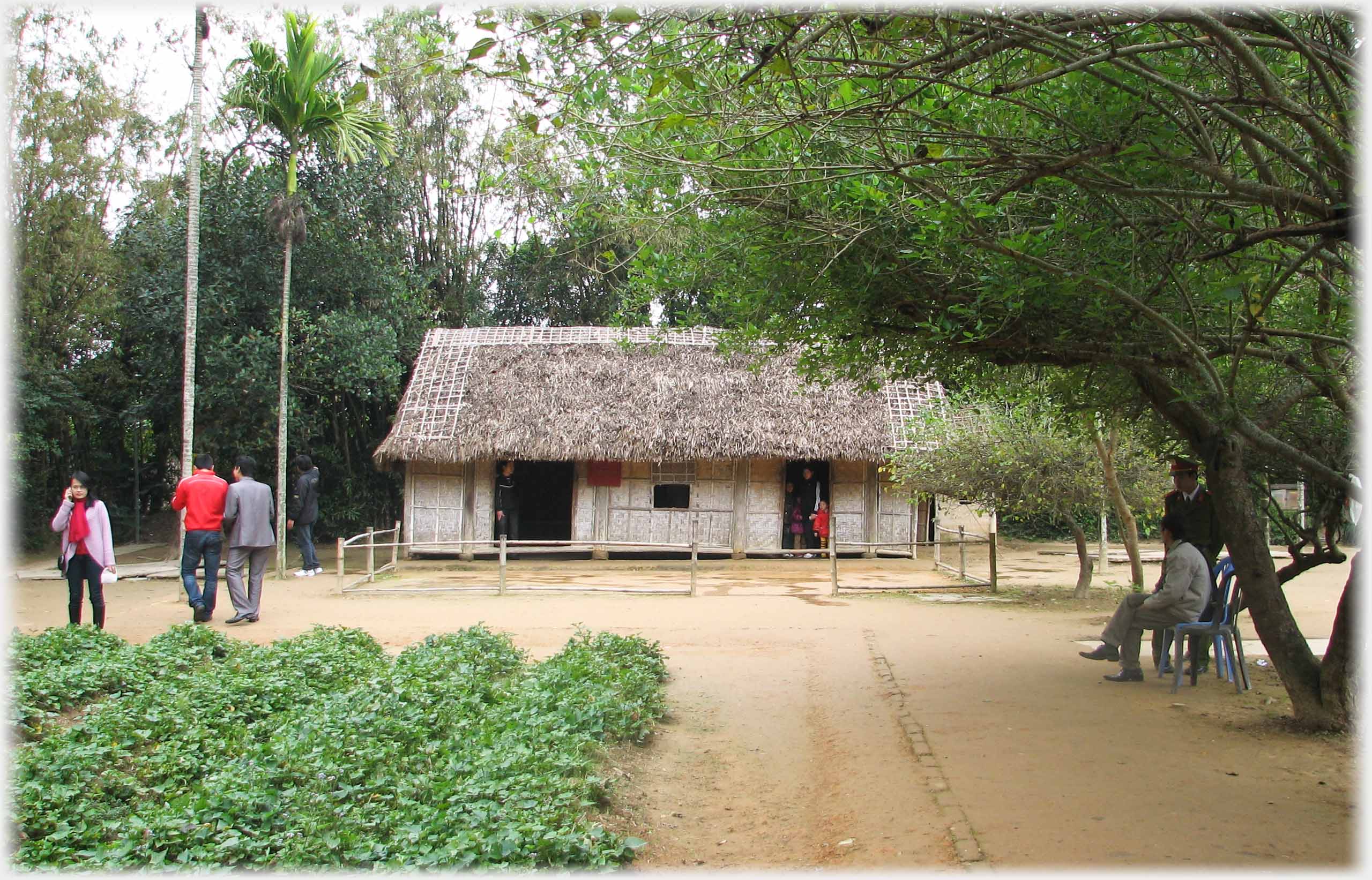 Side viw of thatched house with vegetables in the foreground.