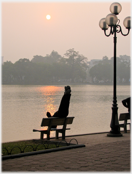 Man with rising sun across the water.