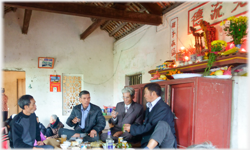 Four men drinking together with an illuminated altar behind them.