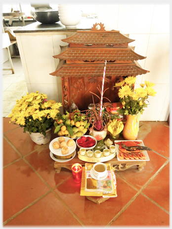 Cafe floor level altar with offerings of fish and cakes.
