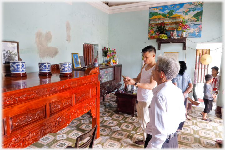 Han with cellphone beside the altar watched by his father.