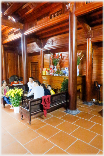 Wooden pillared and panneled room with benches and altar.