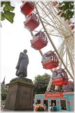 Statue with overhanging ferris wheel.