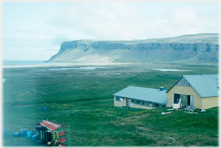 Farm buildings with cliffs beyond.