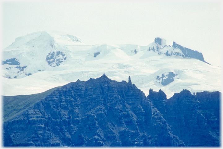 Crags in front of snow covered mountains.