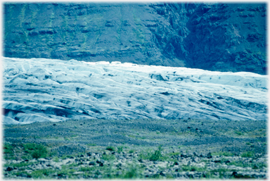 Glacier surface, grass foreground.