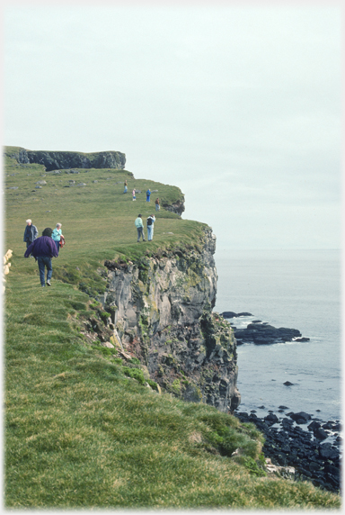 Visitors walking along cliffs near the lighthouse.