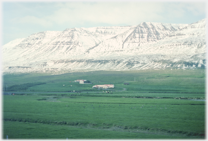 Snow covered mountain ridges with farmhouses below.