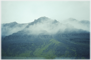 Mist hanging around bleak black crags.