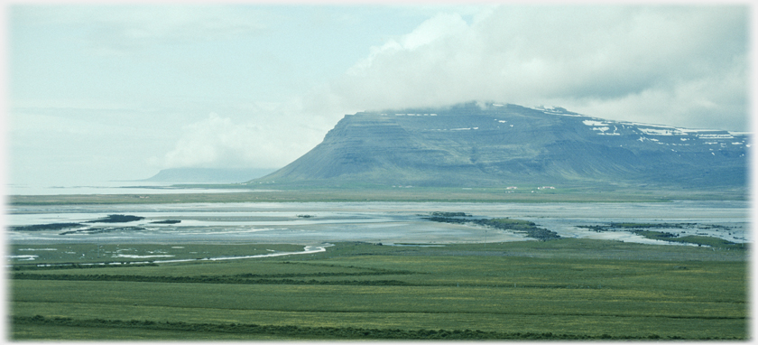 Mountains buttressing out into the sea with cloud capped tops.