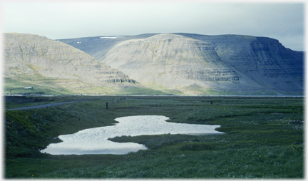 A pool in a depression with high hills beyond.