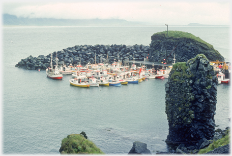 Boats sheltering behind man made extension to a stack.