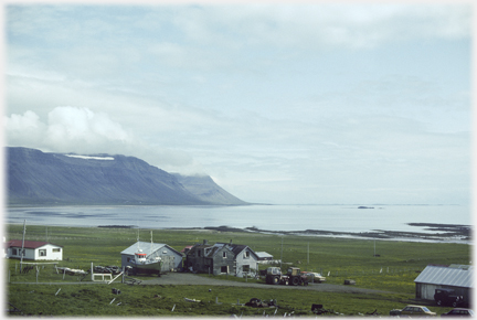 Collection of houses with sea and cliffs
		beyond.