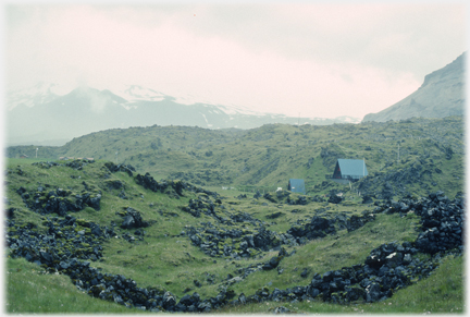 Steep roofed chalets nestling in barren
		rocky landscape.