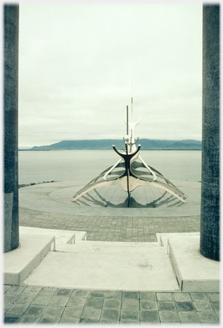 Modern meal sculpture in the form of a
		skeletal boat, framed on plinth.