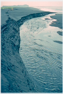 Black sand by stream.