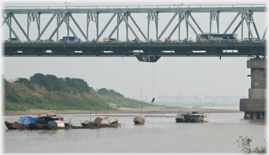 Man descending by rope from a bridge to a boat.